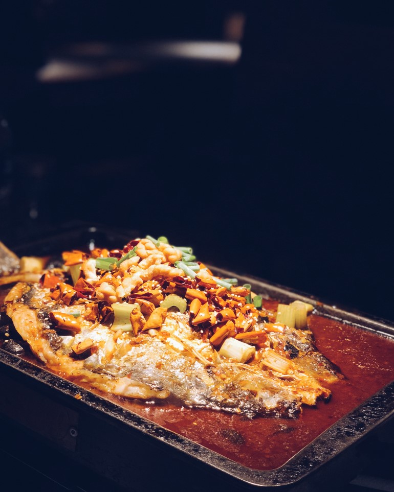 Charcoal grilled fish served on a silver tray.